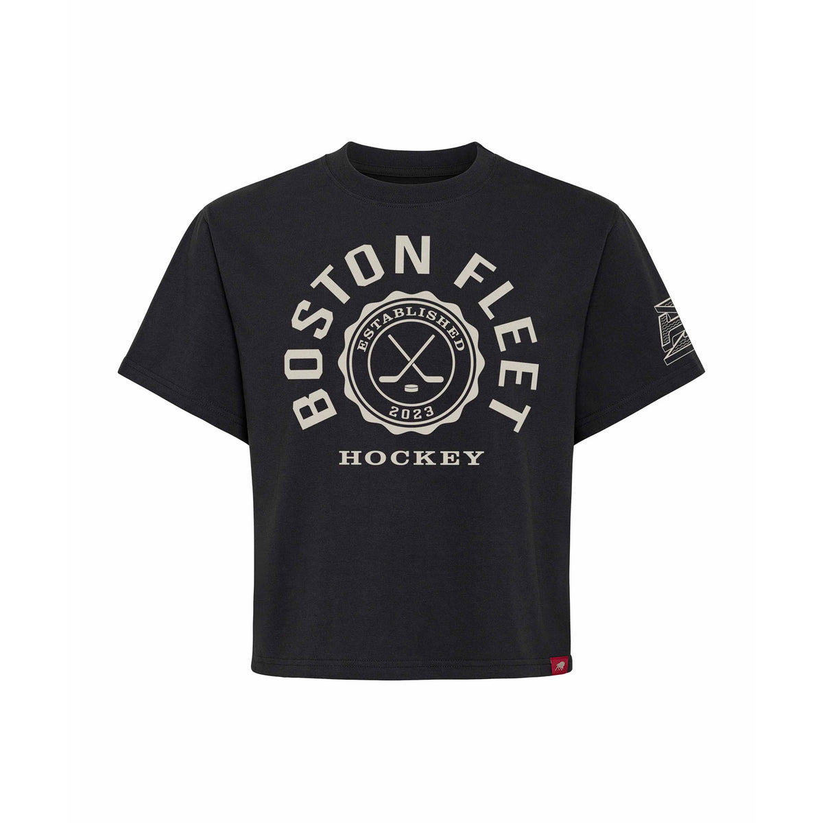 Front of a black short sleeve shirt. 'BOSTON FLEET' is written in a white arch of text around a circular emblem with crossed hockey sticks and 'ESTABLISHED 2023' inside with 'HOCKEY' below it. A white mono-color Boston Fleet logo is on the left sleeve.