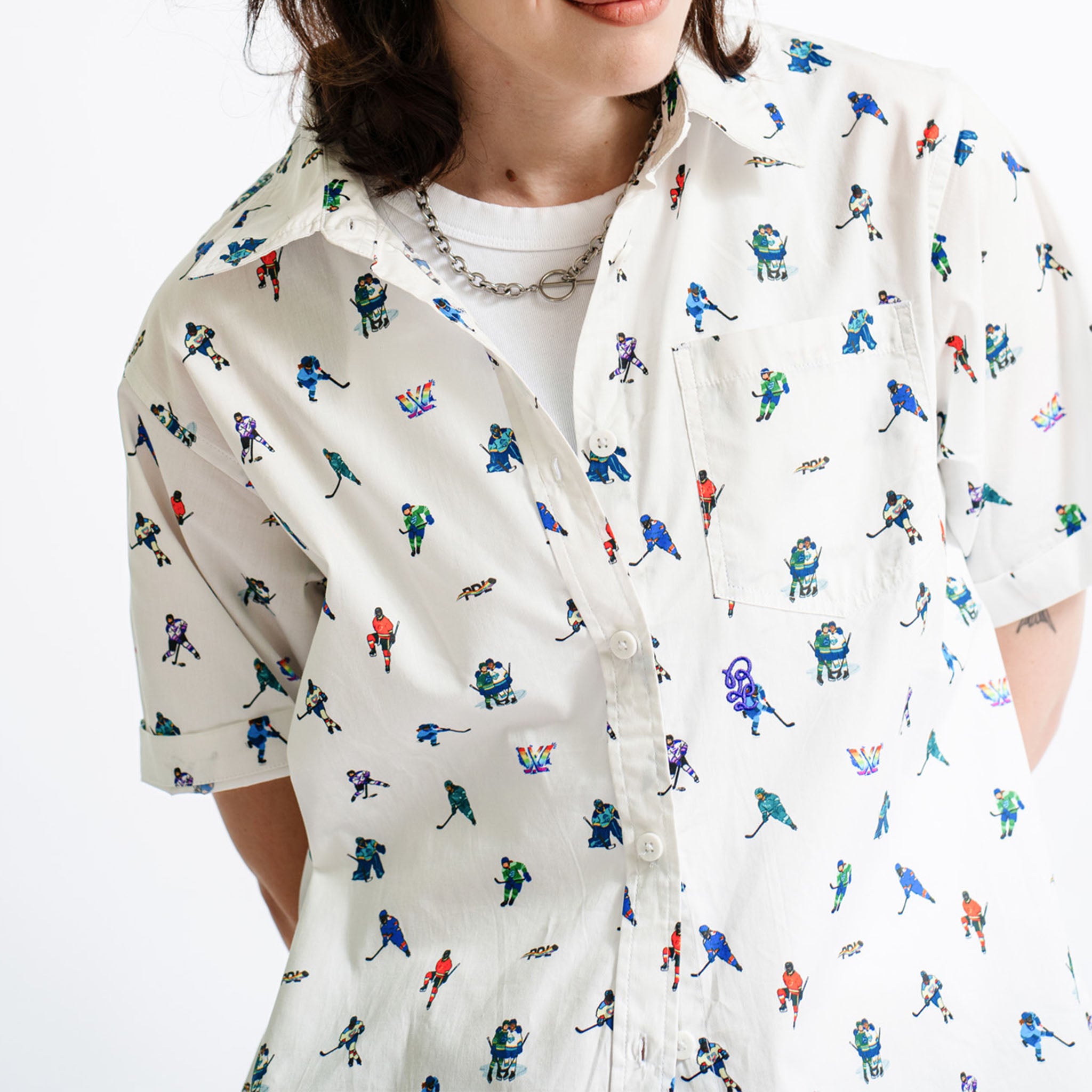 Person wearing a white shirt with colorful graphic pattern on a plain background