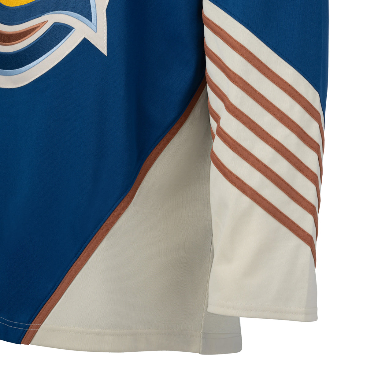 Front of a blue jersey with cream color blocking on the hips with a tan line on top. The sleeves are blue and from the elbow down are cream with small tan stripes.