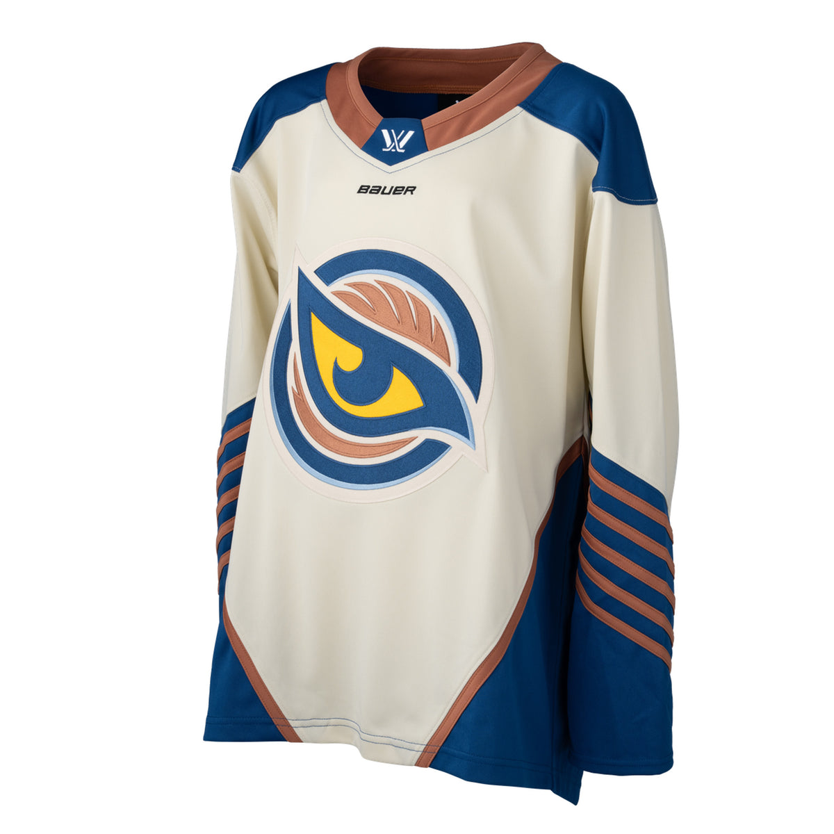Front of a cream-colored jersey with the Vancouver Goldeneyes logo in the center. The hips have blue color blocking with a tan line on top. The tan collar has a blue color block with the PWHL logo and the Bauer logo is beneath it. The blue shoulder caps have the PWHL logo on the left shoulder. The sleeves are cream and from the elbow down are blue with small tan stripes.
