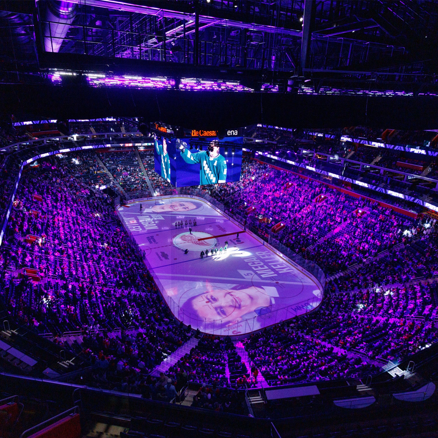Hockey arena with purple lighting and large screen displaying a player's image.