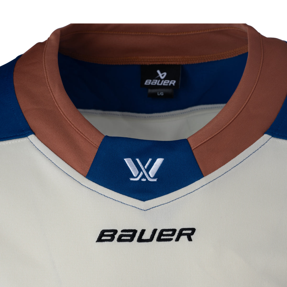 Front of a cream-colored jersey with a tan collar has a blue color block with the PWHL logo and the Bauer logo is beneath it. 