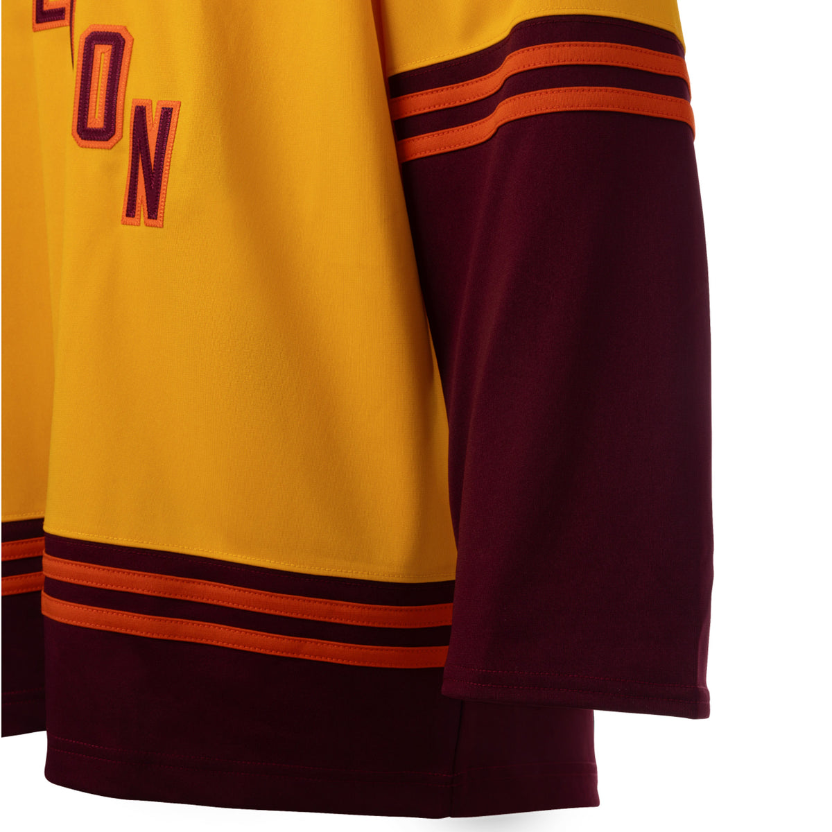 The maroon right shoulder of a gold jersey with orange trim on the collar. A white PWHL logo is on the right shoulder.