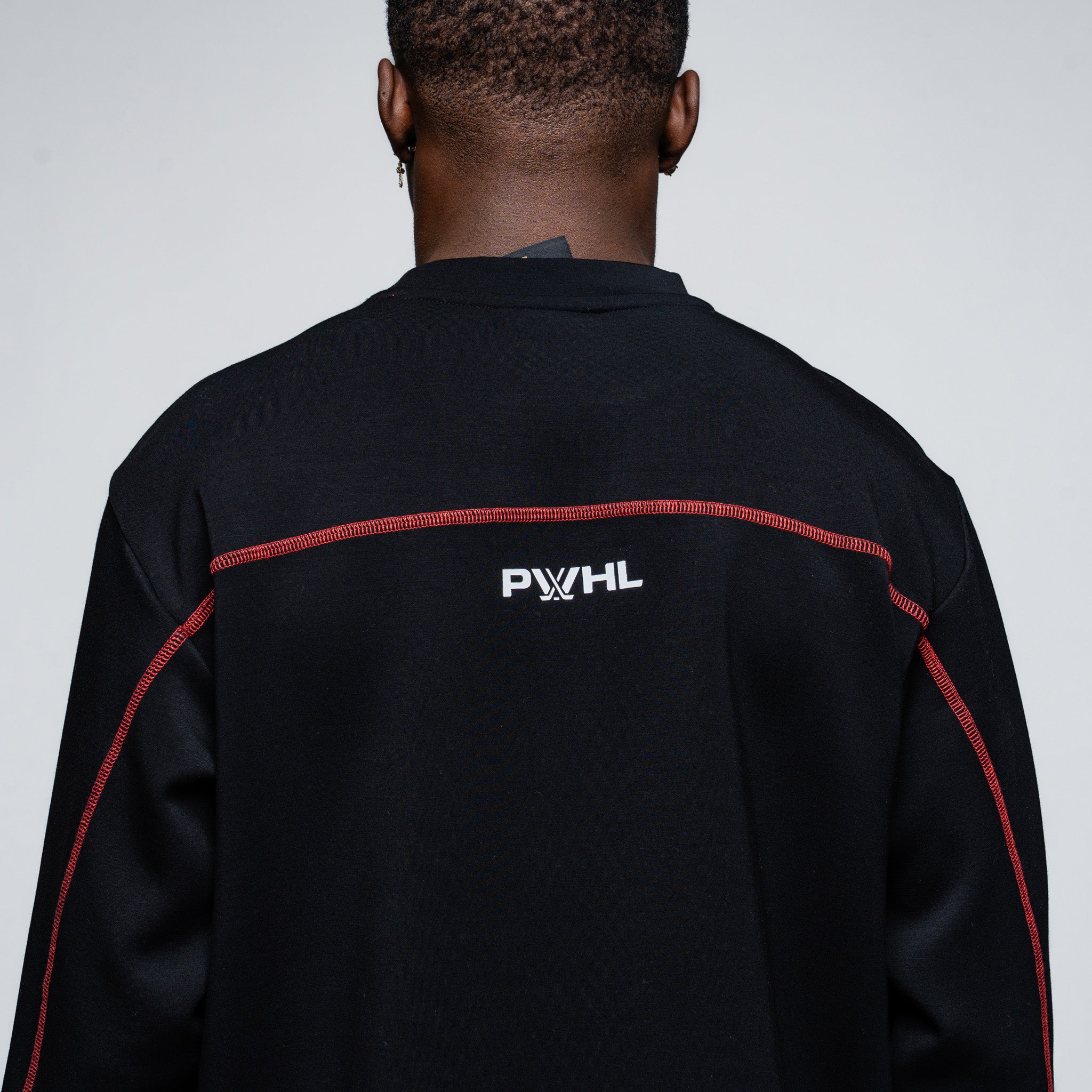 Person wearing a black jacket with 'PWHL' logo on the back against a gray background