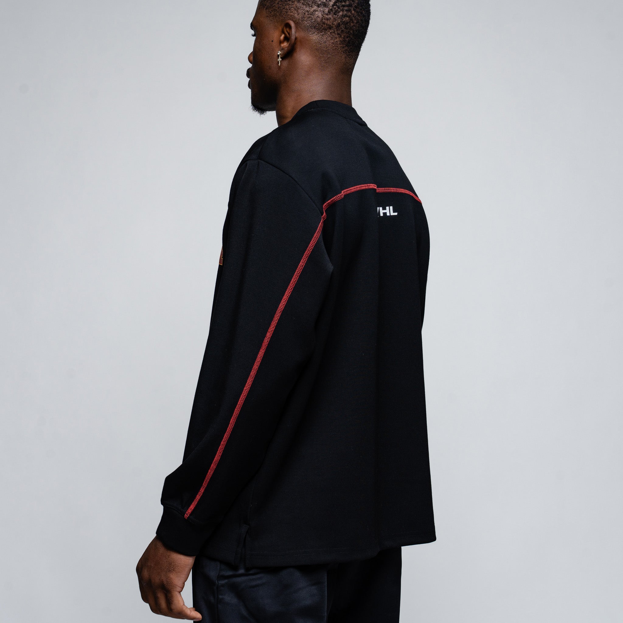 Person wearing a black long-sleeve shirt with red accents on a plain background