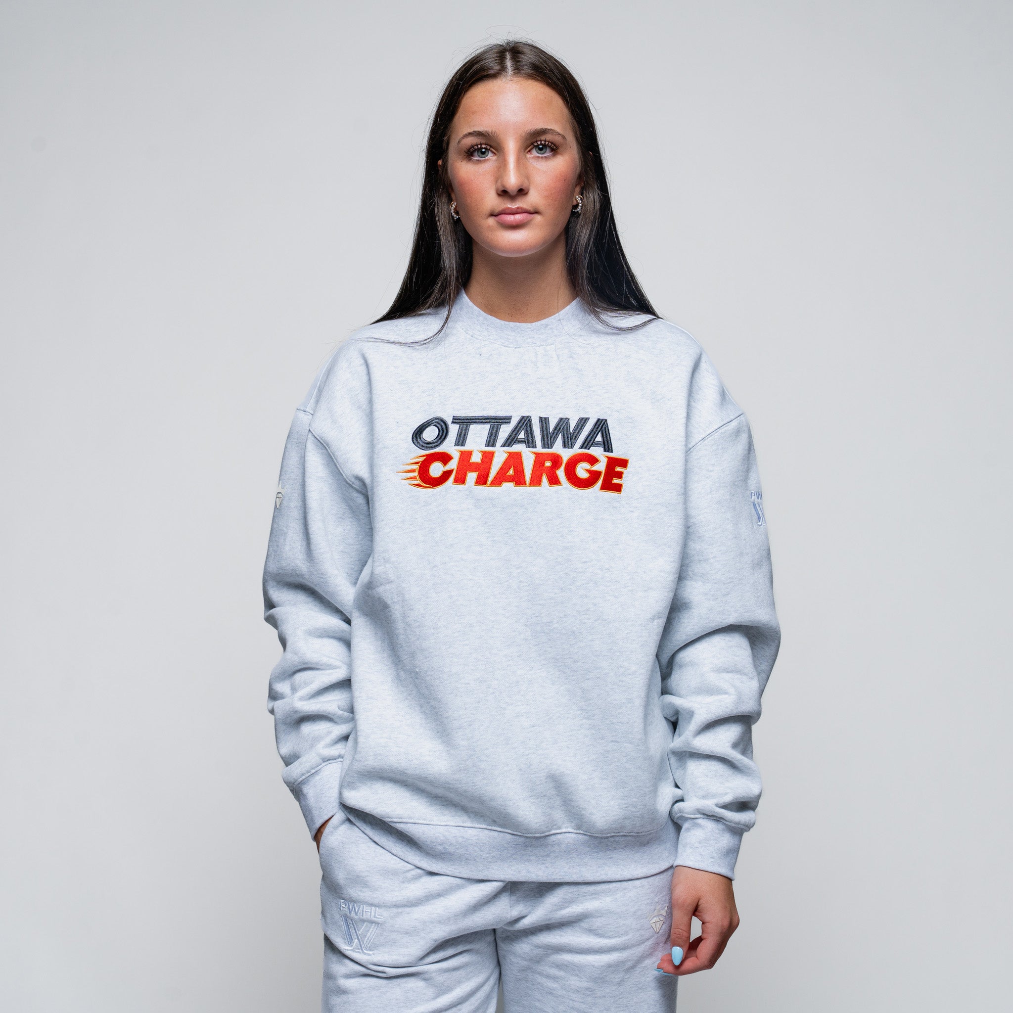Person wearing a light gray sweatshirt with 'Ottawa Charge' text on a plain background