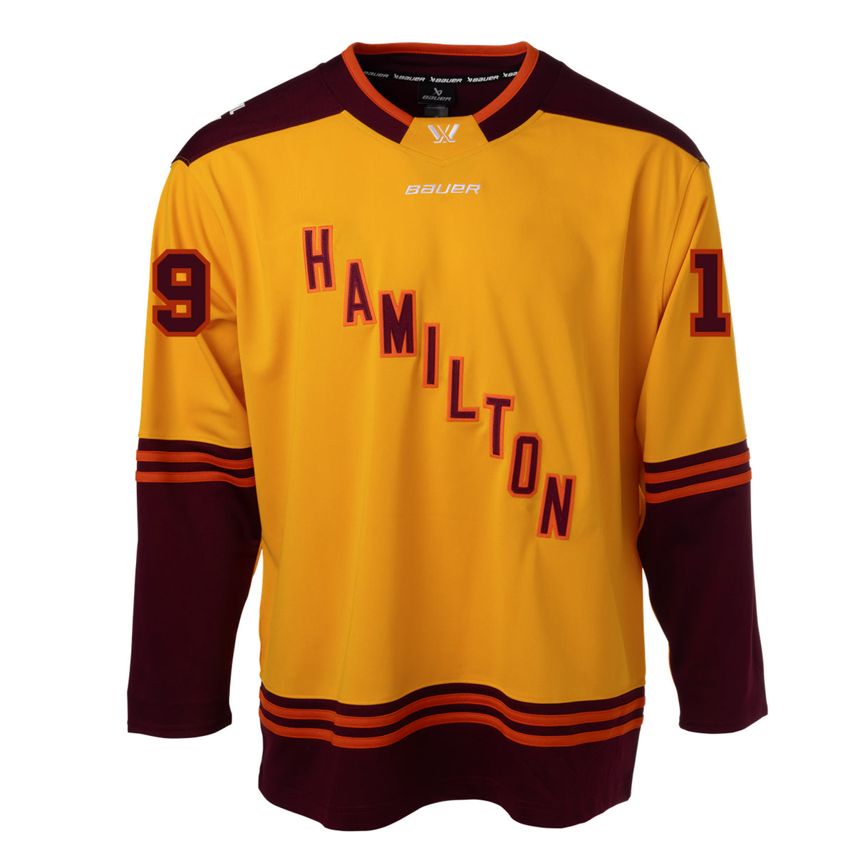 Front of a gold jersey with maroon shoulder caps. Maroon color blocking on the sleeves and bottom hem with orange stipes on top. 'HAMILTON' is in maroon with orange outlining diagonally across the chest with '19' on each sleeve. The collar is maroon with orange trim and a gold color block in front showcasing a white PWHL logo with a Bauer logo below it. 
