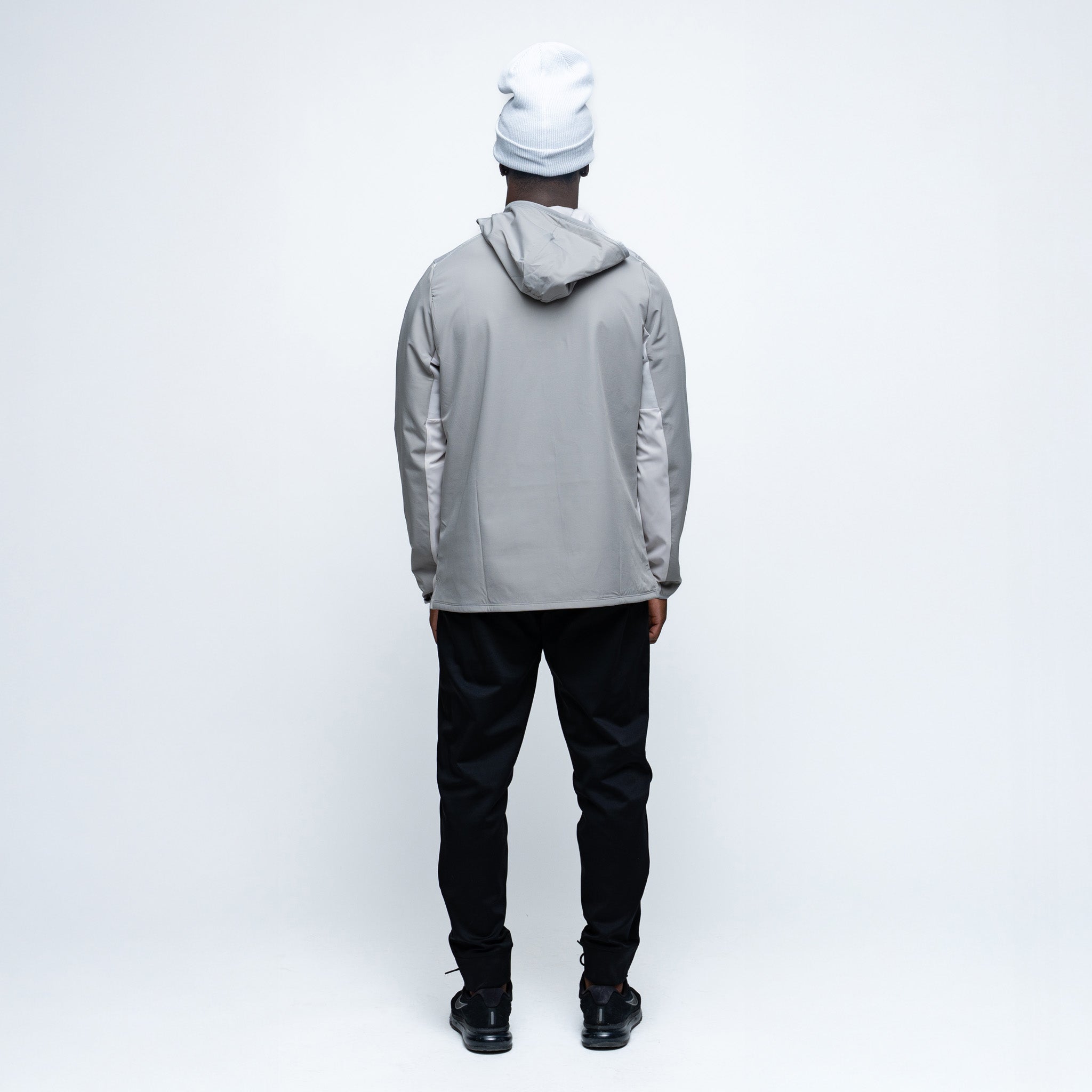 Person wearing a gray jacket, black pants, and white beanie on a white background